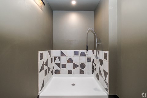 A white bathroom sink with a black and white tiled wall.