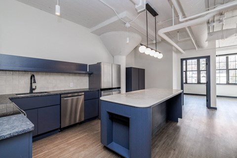 A kitchen with dark blue cabinets and a stainless steel dishwasher.