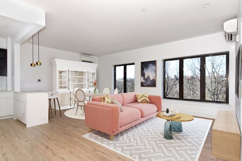 a living room with a pink couch and a kitchen with a table and chairs