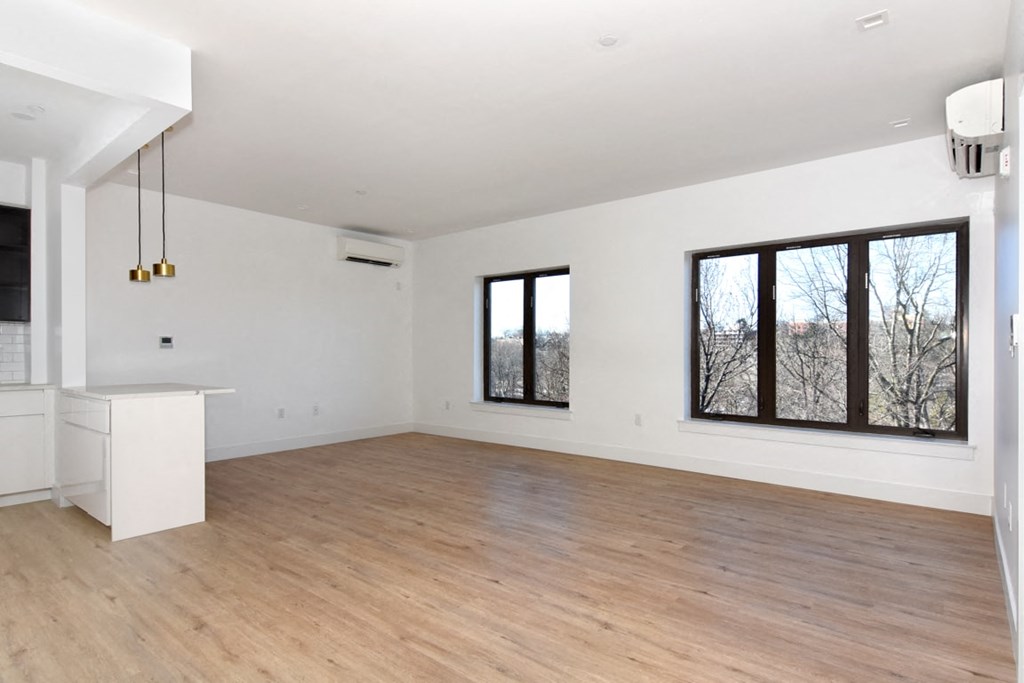 a living room with white walls and wood floors and large windows