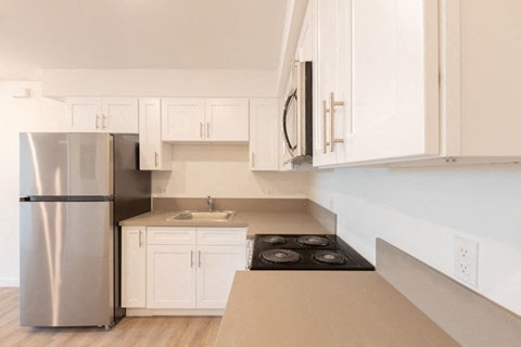 A modern kitchen with white cabinets and a stainless steel refrigerator.