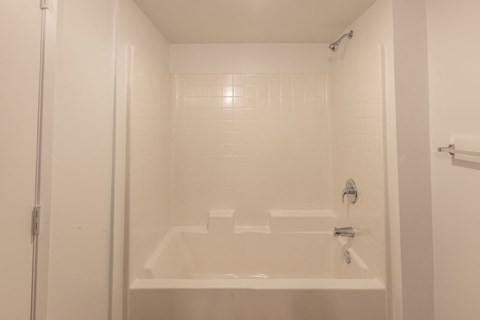 A white bathroom with a shower and a white tub.