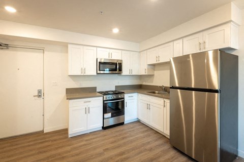 A modern kitchen with a stainless steel refrigerator and white cabinets.