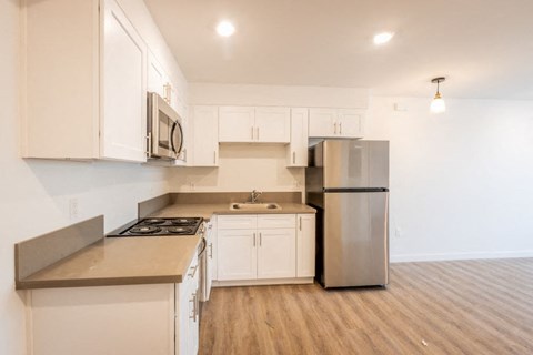 A kitchen with white cabinets and a stainless steel refrigerator.