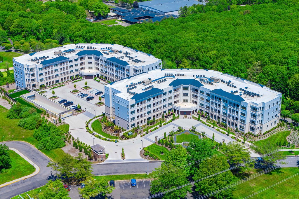A large white building with a blue roof is surrounded by greenery.