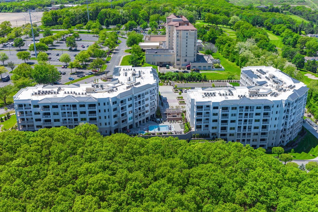 A large white building with a red roof is surrounded by trees.
