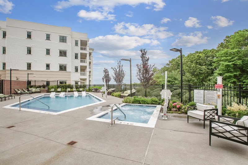 A pool area with two pools and a building in the background.