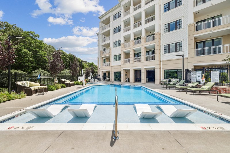 A large swimming pool in front of a white apartment building.