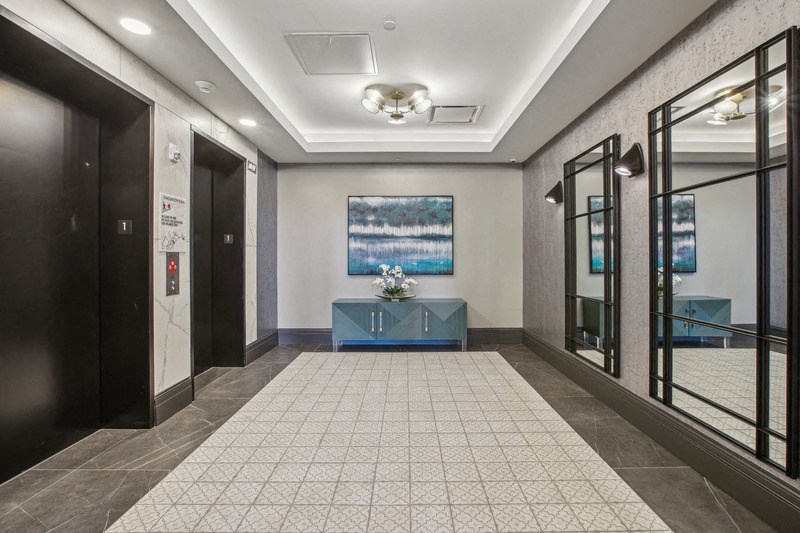 a lobby with doors and a table and a painting on the wall