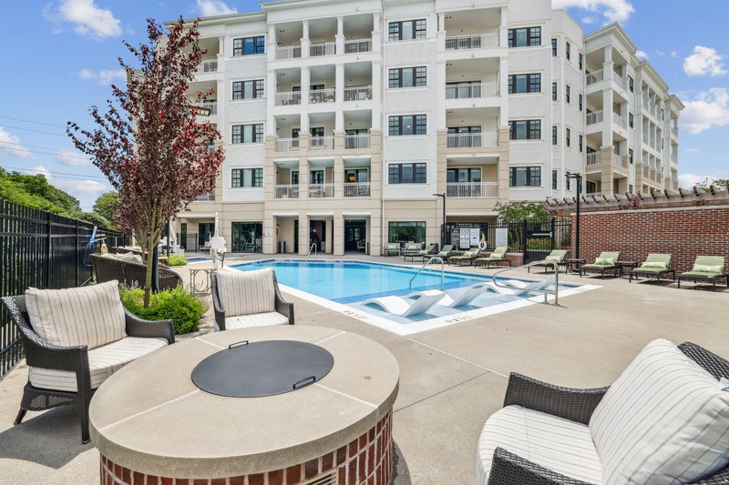 A large white apartment building with a pool in the backyard.