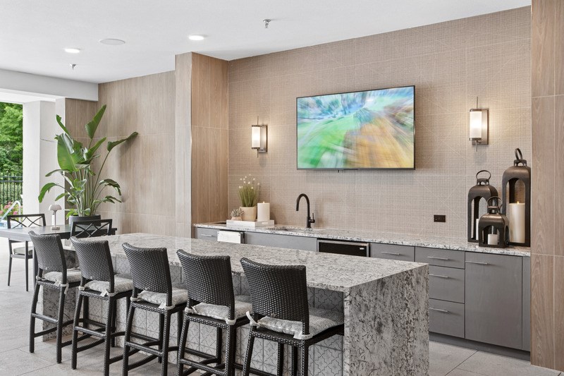 A modern kitchen with a marble countertop and bar stools.