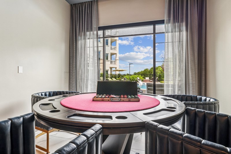A round table with a pink tablecloth in the middle surrounded by black leather chairs.