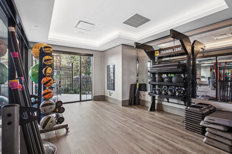 the home gym has plenty of equipment and a glass door