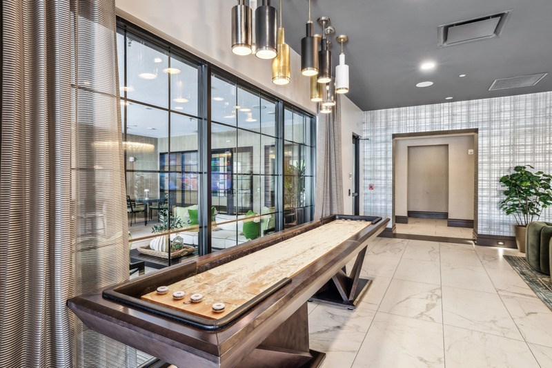 A long wooden table with a tray of food on it sits in a modern room with a glass wall.