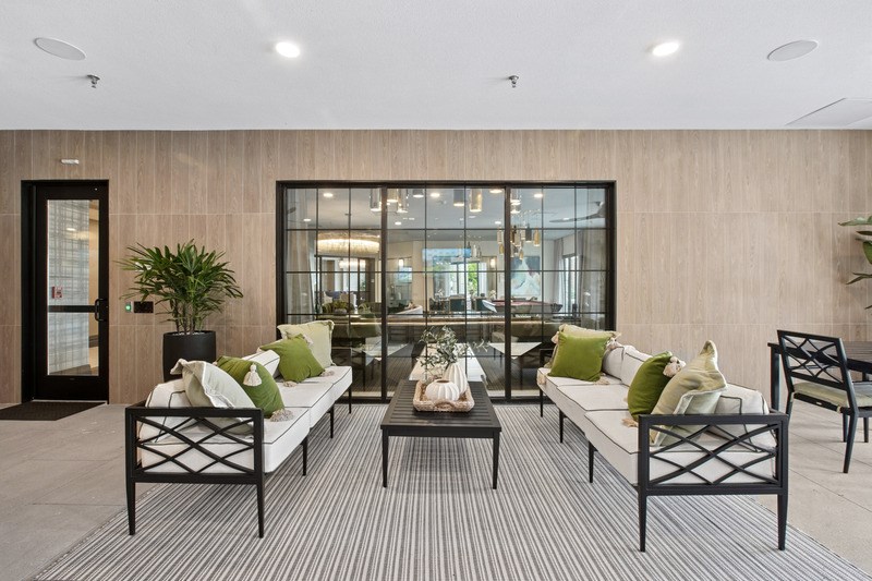 A modern living room with a glass door and a grey sofa.