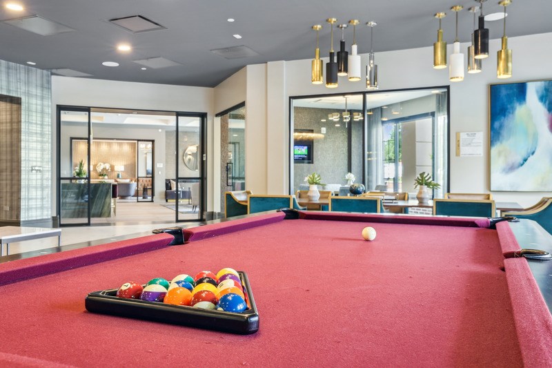 A pool table with a red cloth and a white ball in the middle.