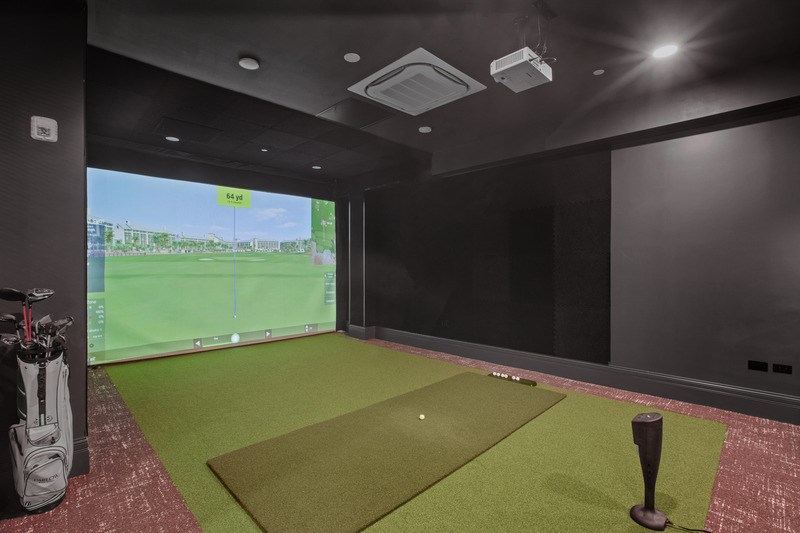 A room with a golf simulator and a golf bag on the floor.