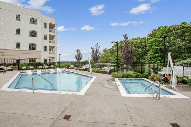 A large outdoor swimming pool surrounded by a fence and trees.