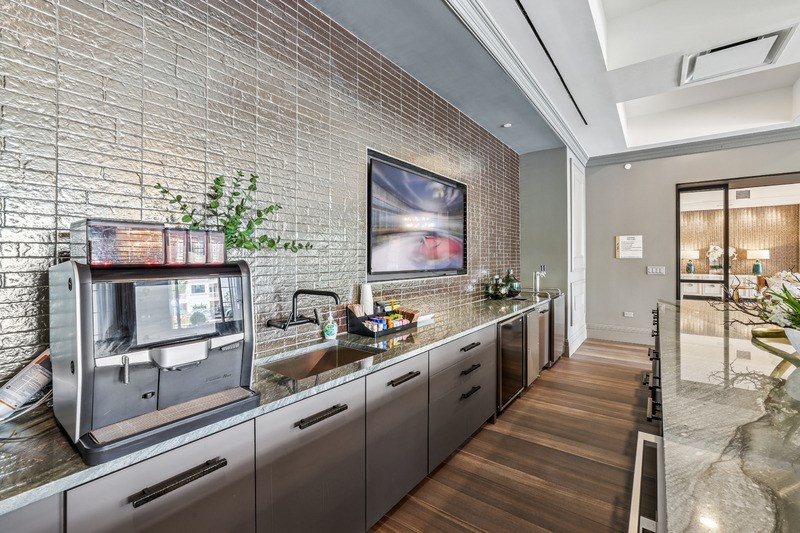 A modern kitchen with a stainless steel refrigerator and wooden flooring.