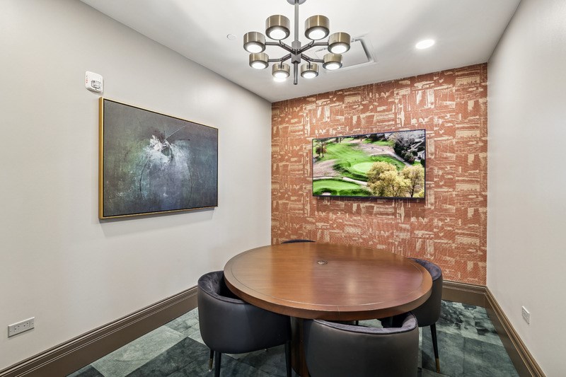 A room with a round table and chairs and a painting on the wall.