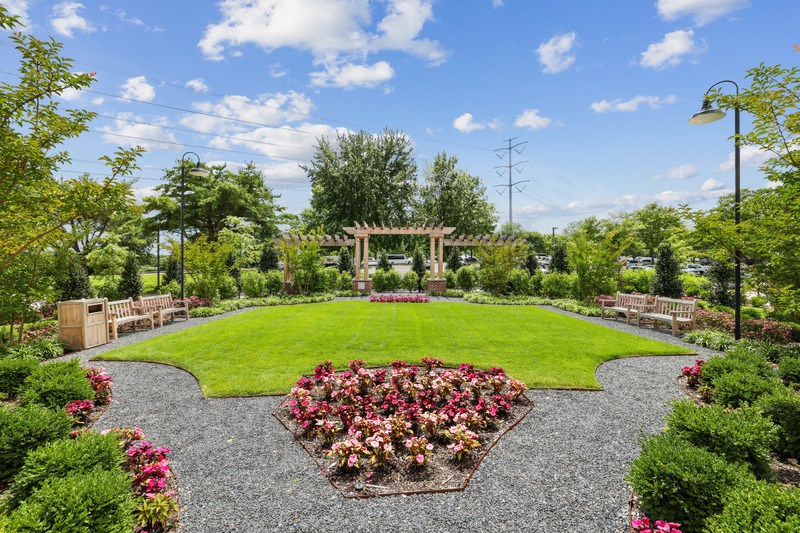 A beautifully landscaped garden with a gravel pathway and a flower bed in the center.