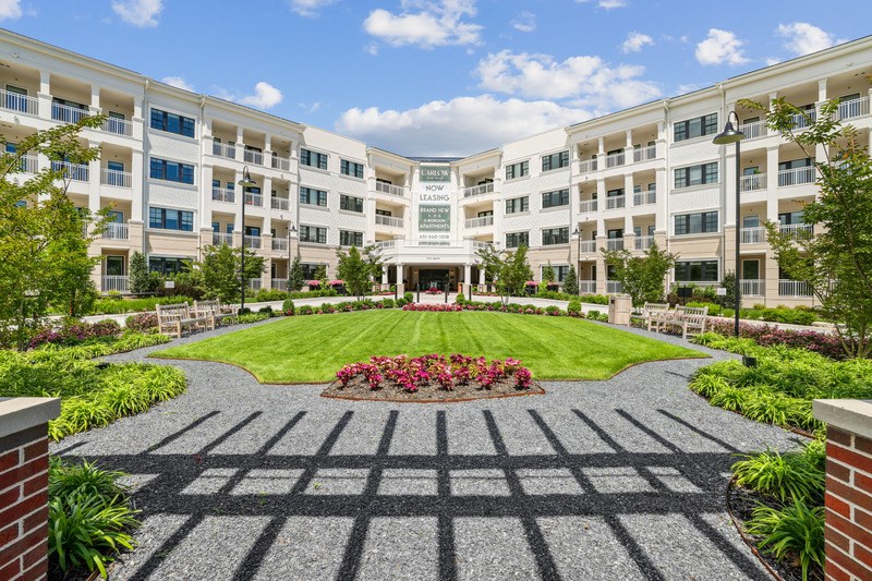A courtyard with a brick patterned ground and a building in the background.