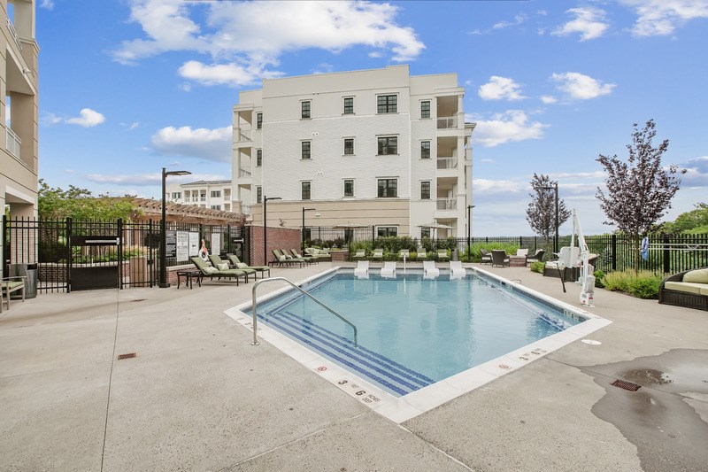 A swimming pool in front of a white apartment building.