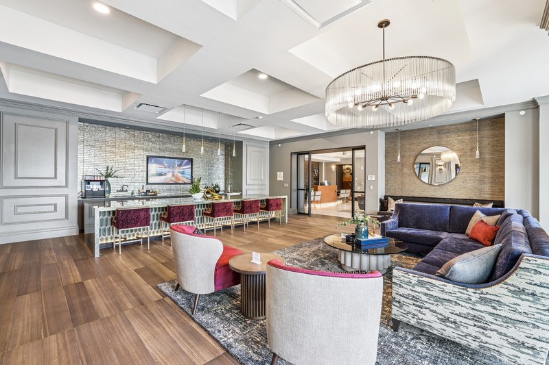 A modern living room with a large sofa, a coffee table, and a TV on the wall.