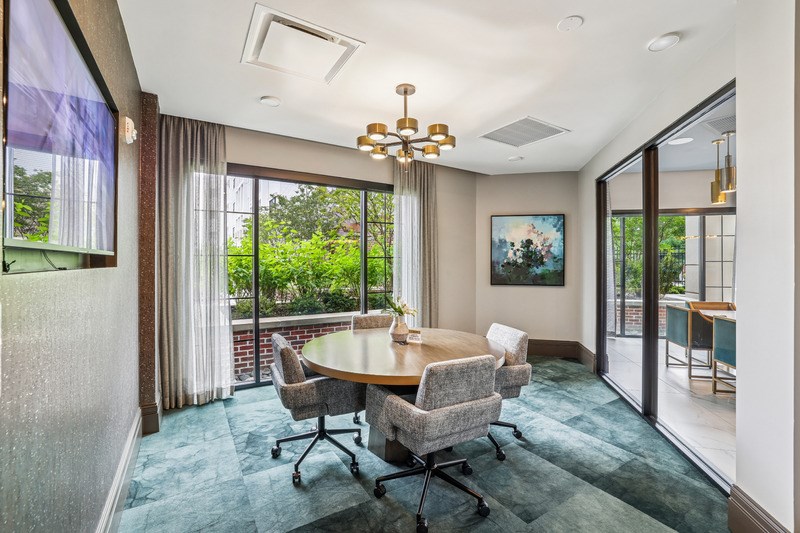 A conference room with a table and chairs and a painting on the wall.