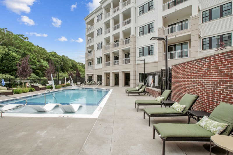 A pool area with lounge chairs and a building in the background.