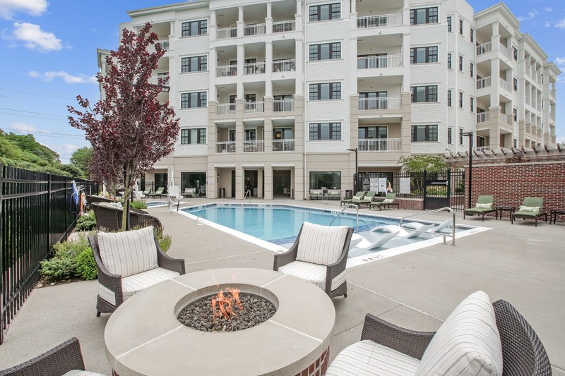 A fire pit sits in the middle of a patio with chairs around it.