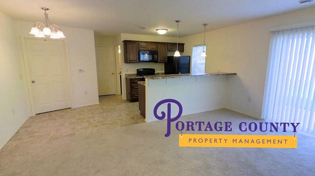 an empty living room and kitchen with a counter and a door