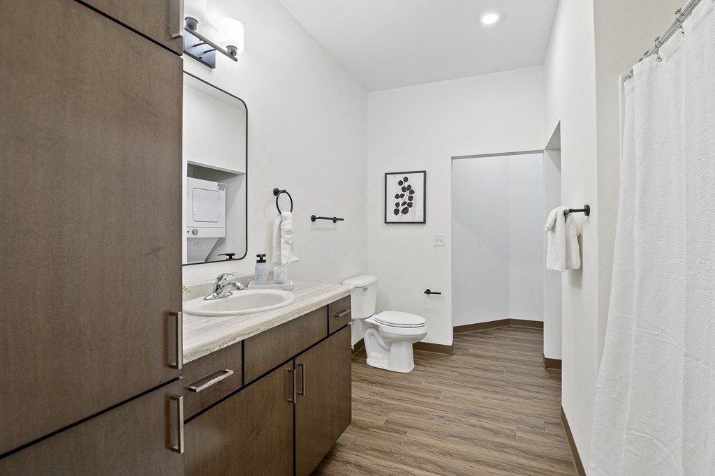A bathroom with a toilet, sink, and mirror.