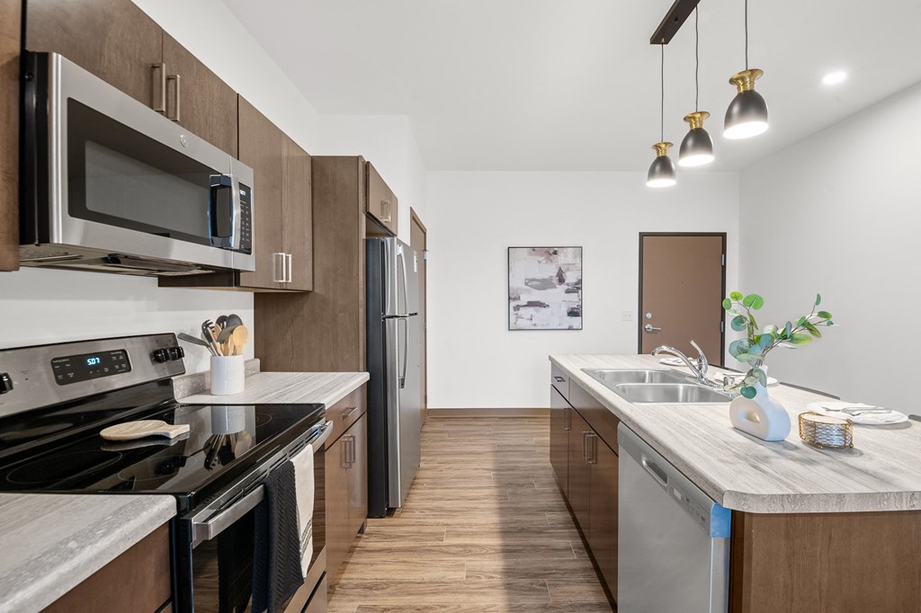 A modern kitchen with dark wood cabinets and stainless steel appliances.