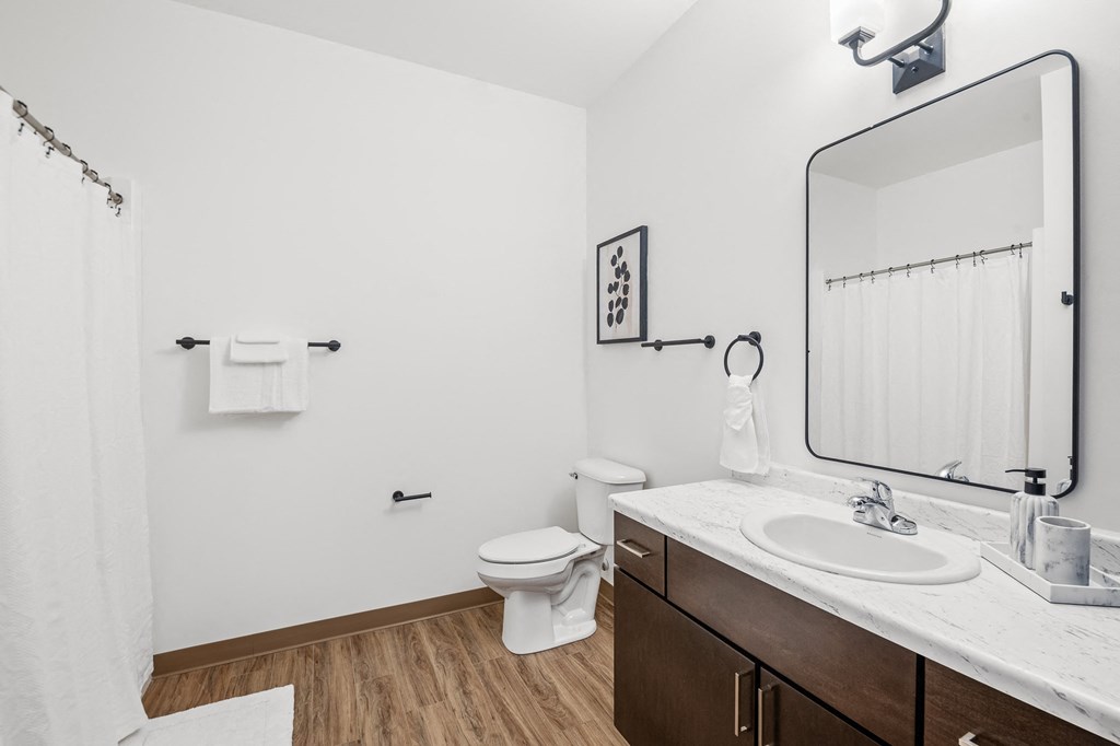 A white bathroom with a toilet, sink, and mirror.