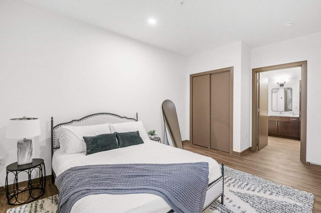 A bedroom with a bed, a lamp, and a rug.