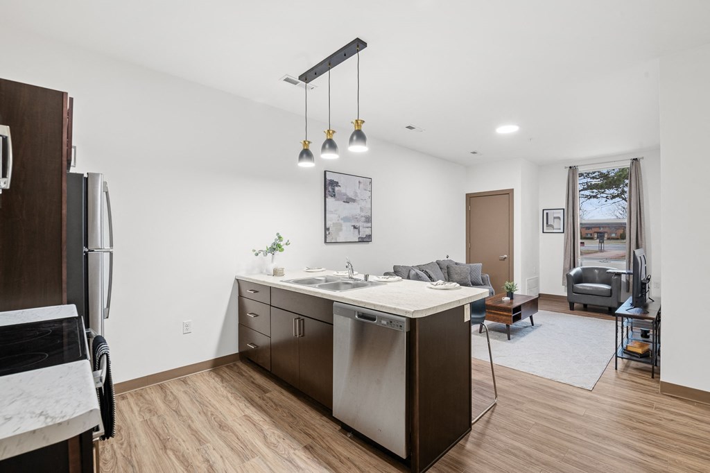 A kitchen with a white dishwasher and wooden floors.