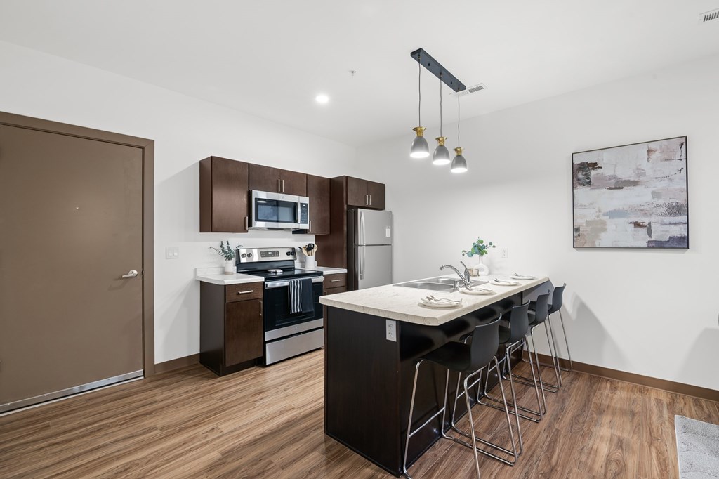 A modern kitchen with dark wood floors and white walls.