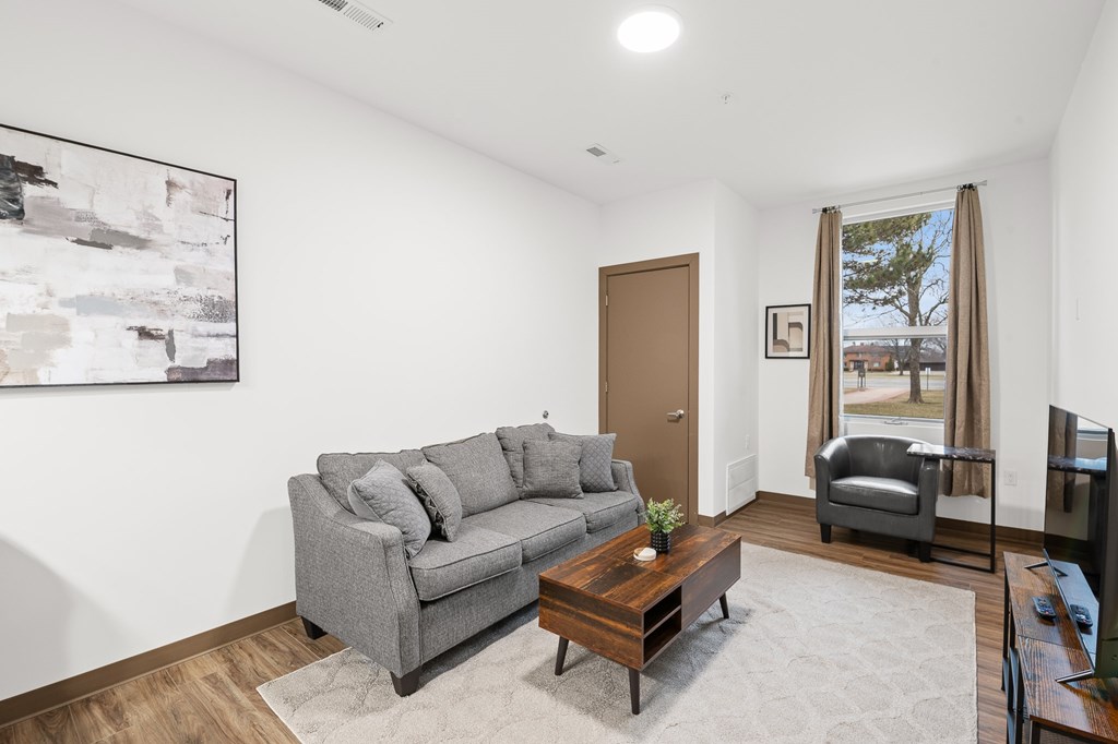 A living room with a grey couch, a coffee table, and a painting on the wall.