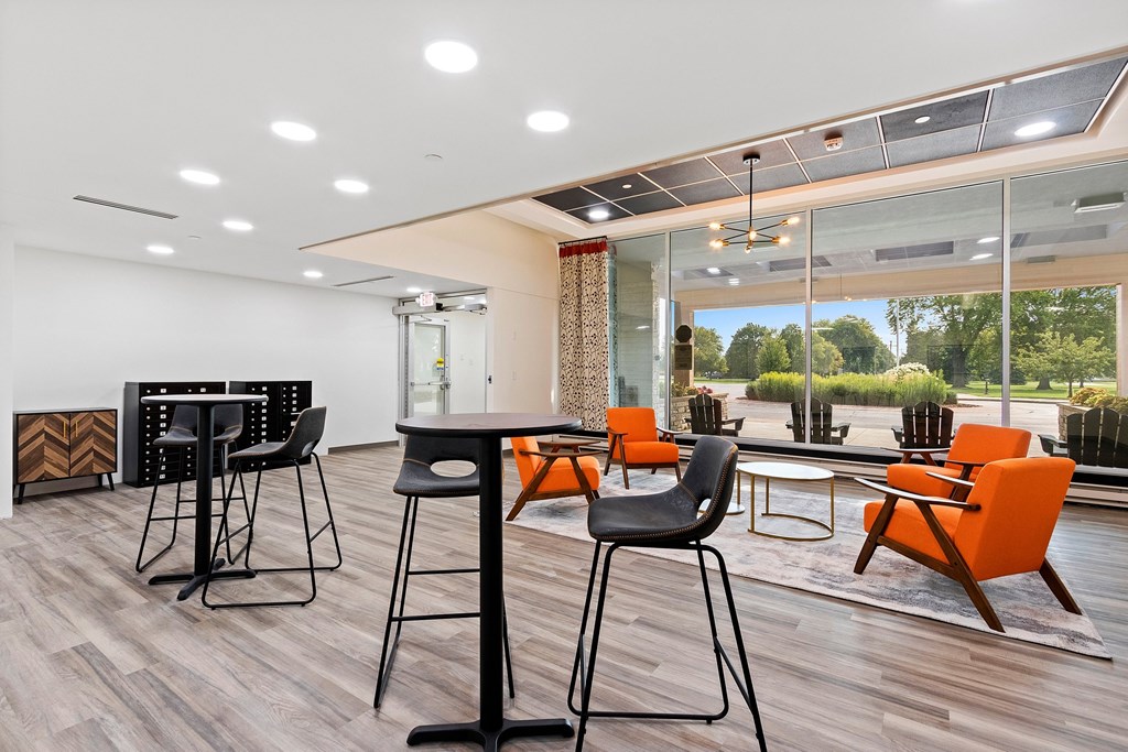 A modern dining room with a glass table and orange chairs.