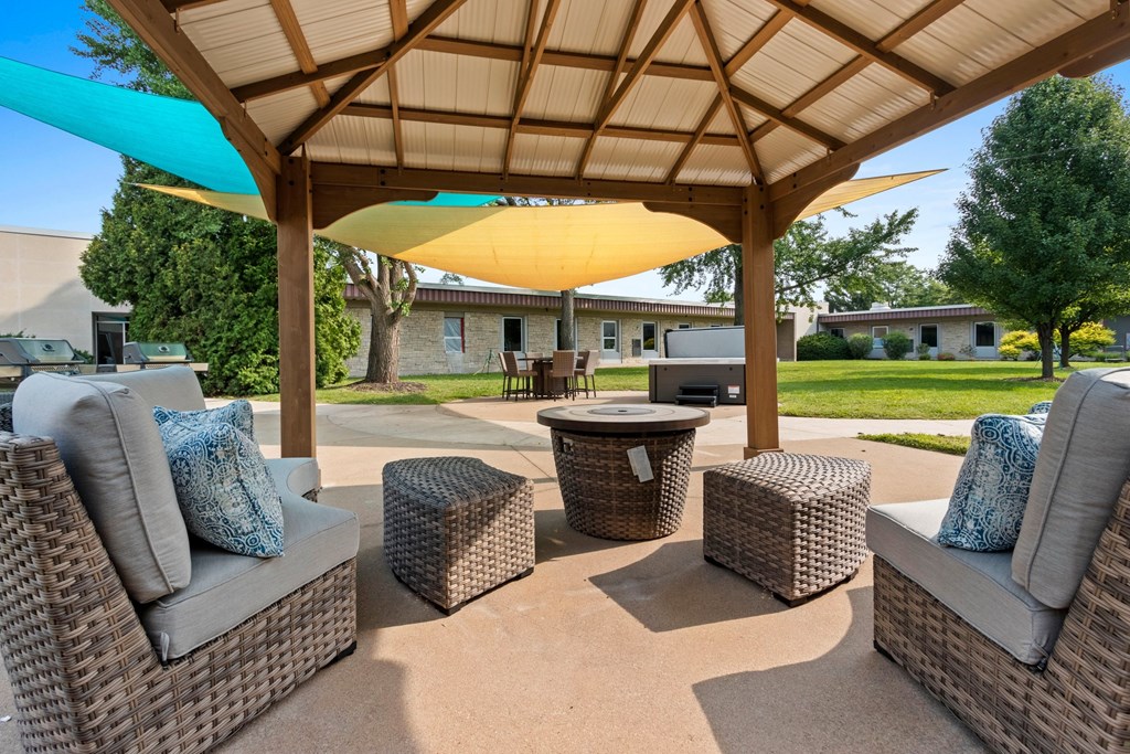 A patio with a wicker sofa, table and chairs under a canopy.