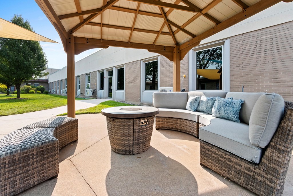 A patio with a wicker sofa and table under a wooden roof.