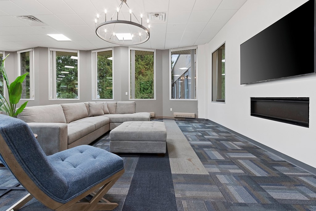 A modern living room with a grey sofa, a blue chair, and a grey rug.