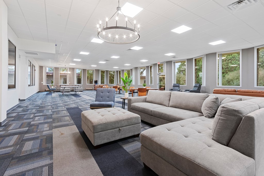A spacious living room with grey couches and a patterned carpet.