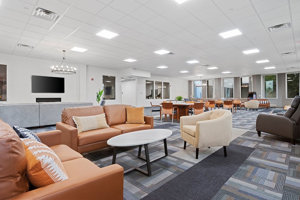 A modern office lounge with orange and beige couches and a television.