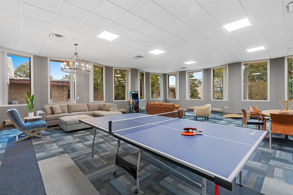 A ping pong table is in the middle of a room with a blue carpet.