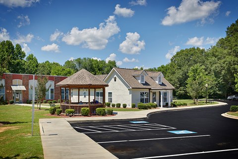 A small white building with a porch is surrounded by a parking lot.