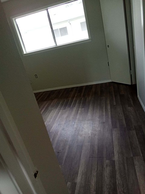 an empty room with wooden floors and a window