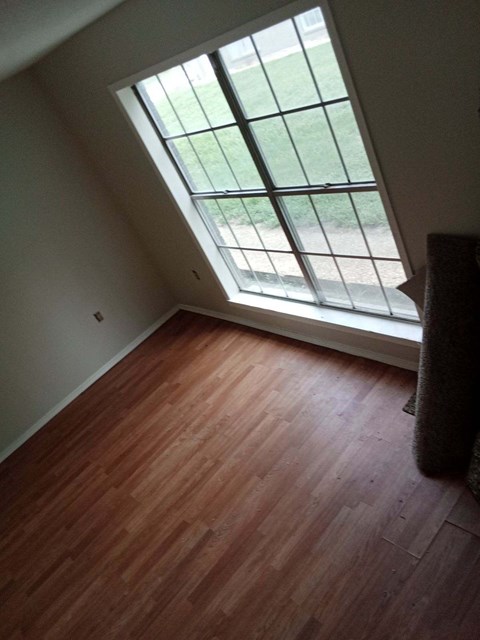 an empty living room with wood floors and a large window