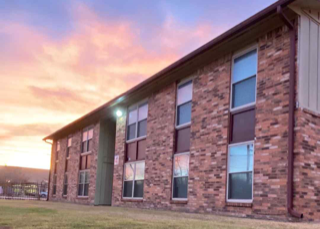 A building with a red brick facade and a green trimmed window.